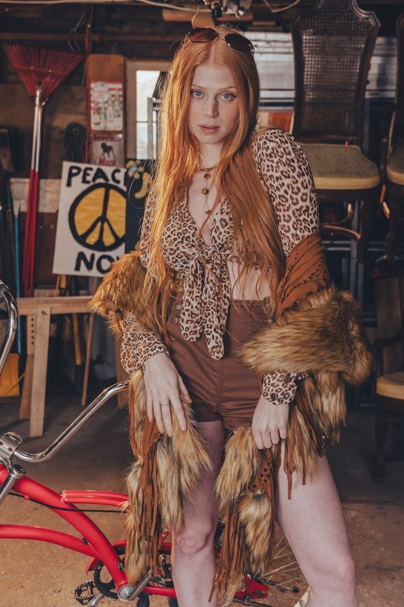 Person wearing a leopard print top and brown skirt with fur accents in an indoor setting.