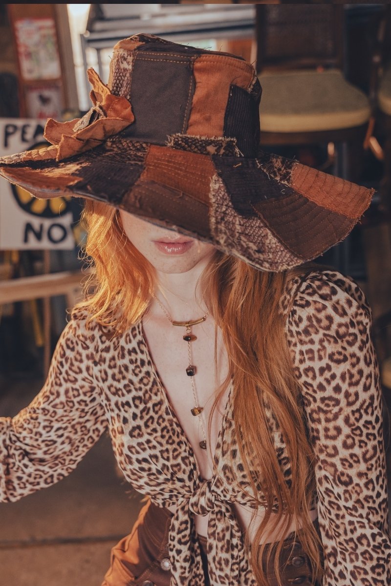 Person wearing a patchwork hat and leopard print outfit in an indoor setting