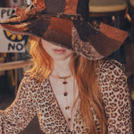 Person wearing a patchwork hat and leopard print outfit in an indoor setting