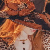 Close-up of a decorative hat with floral details and leopard print fabric.