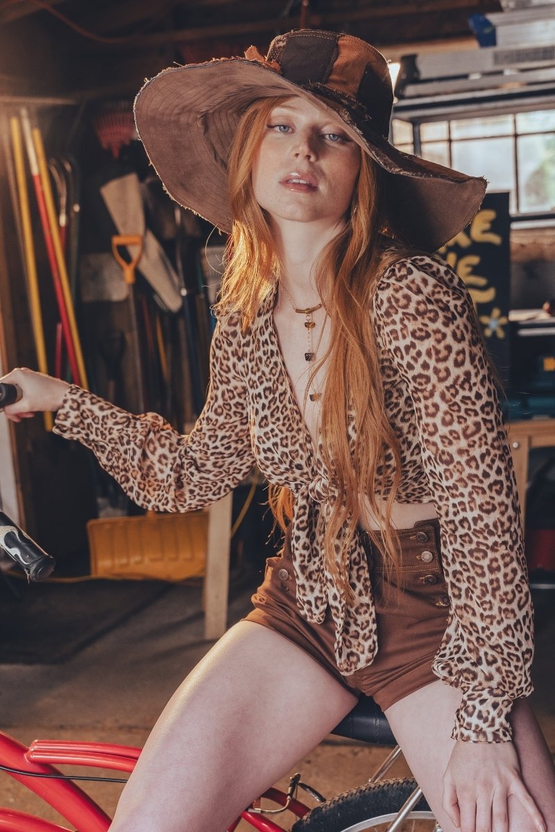 Woman in leopard print outfit sitting on a bike in an indoor setting