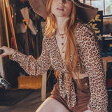 Woman in leopard print outfit sitting on a bike in an indoor setting