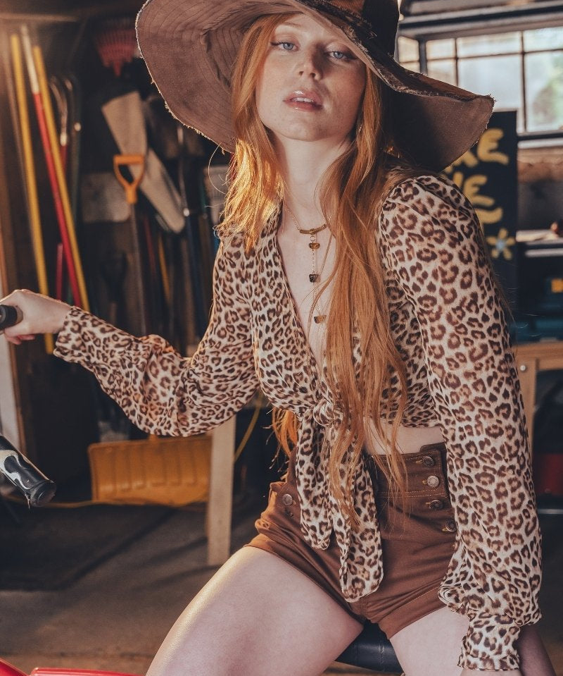 Woman in leopard print outfit sitting on a bike in an indoor setting