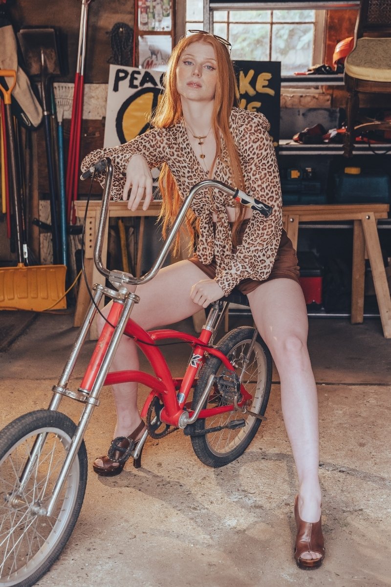 Woman sitting on a red bicycle in a workshop setting