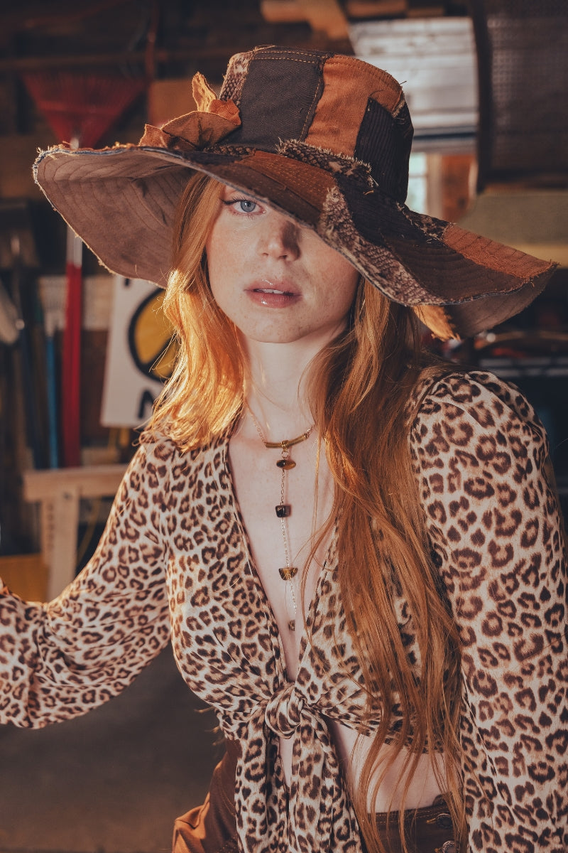 Woman wearing a leopard print outfit and large hat in an indoor setting
