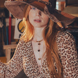 Woman wearing a leopard print outfit and large hat in an indoor setting