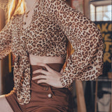 Person wearing a leopard print top and brown shorts in an indoor setting.