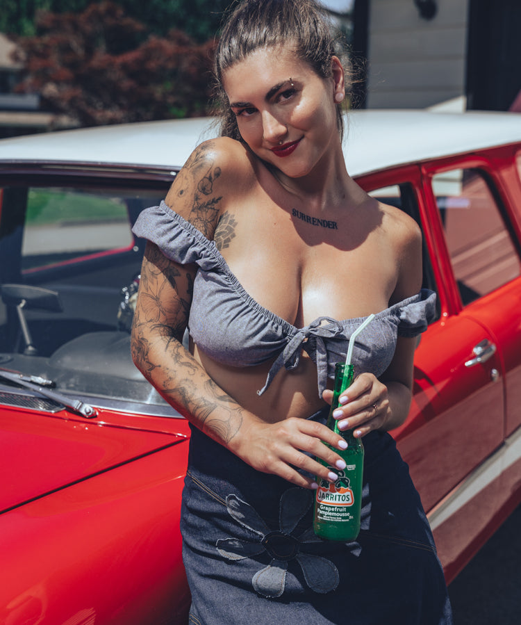 Soul Sisters Bridget Bardot crop top  and flower power skirt on model in front of red hot rod holding retro soda pop