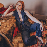 Woman sitting on a patterned rug in a room with a guitar and wall art.