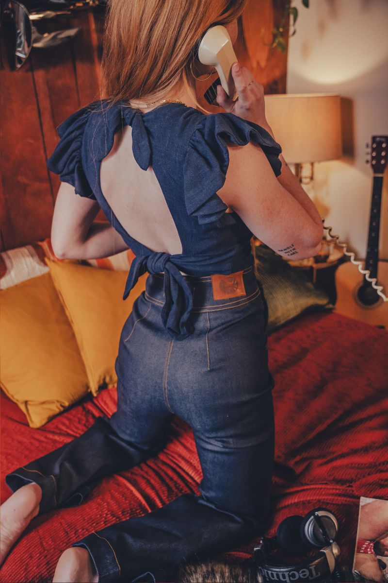 Person wearing a blue top with ruffled sleeves in a bedroom setting.