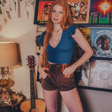 Person standing in a room with vinyl records and a guitar