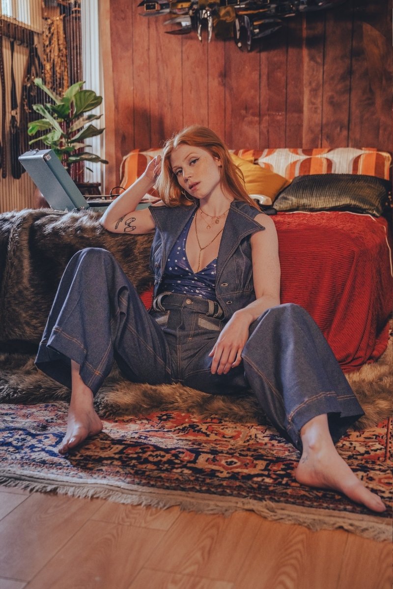 Woman sitting on a rug in a cozy living room with a laptop.