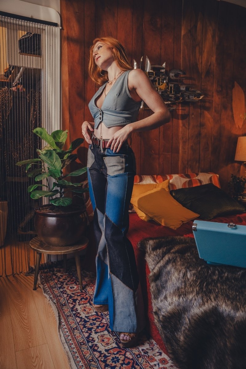 Woman in a room with wooden walls and a patterned rug, wearing a blue top and jeans.