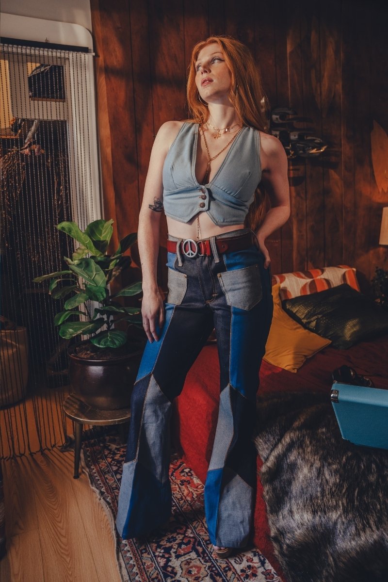 Woman in a stylish outfit standing in a room with wooden walls and a plant.