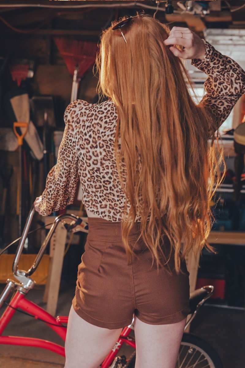 Woman with long blonde hair standing in a garage with a red bicycle.