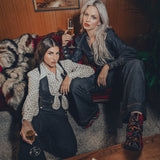 high waisted bell bottoms and tailored waistcoat steal the show as 2 women lounge in a throwback 70s home setting