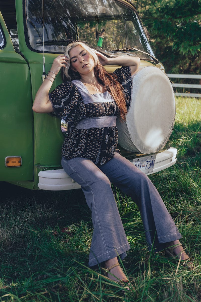 Girl sits at the front of a 1970s VW Van wearing 70s fashion jeans and blouse