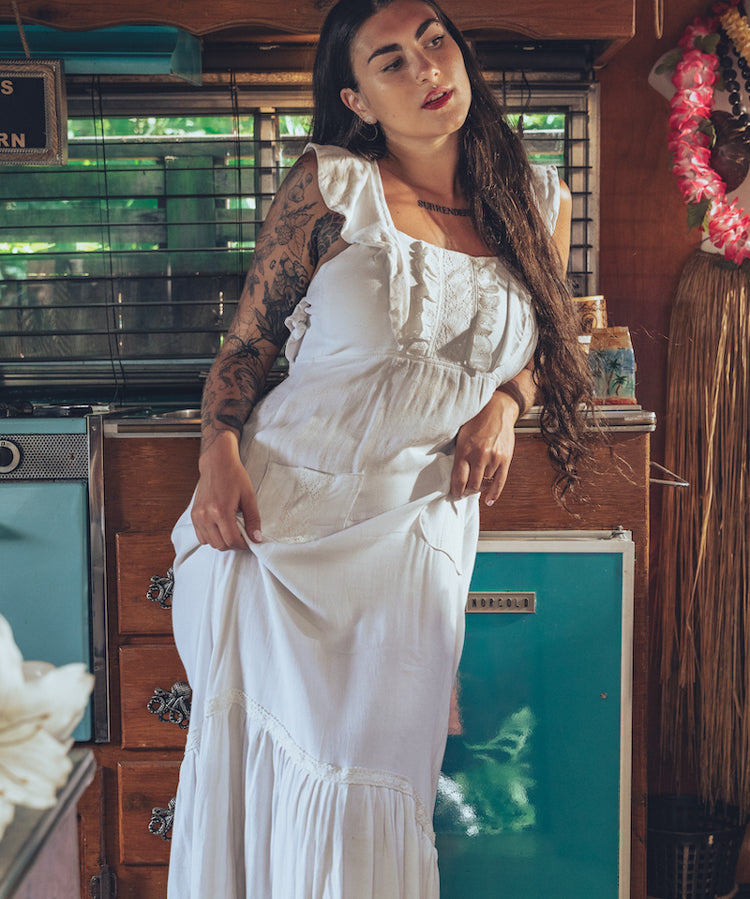 Soul Sister since 1969 long white dress on beautiful woman with a fringe shawl and retro floppy hat standing in a vintage trailer