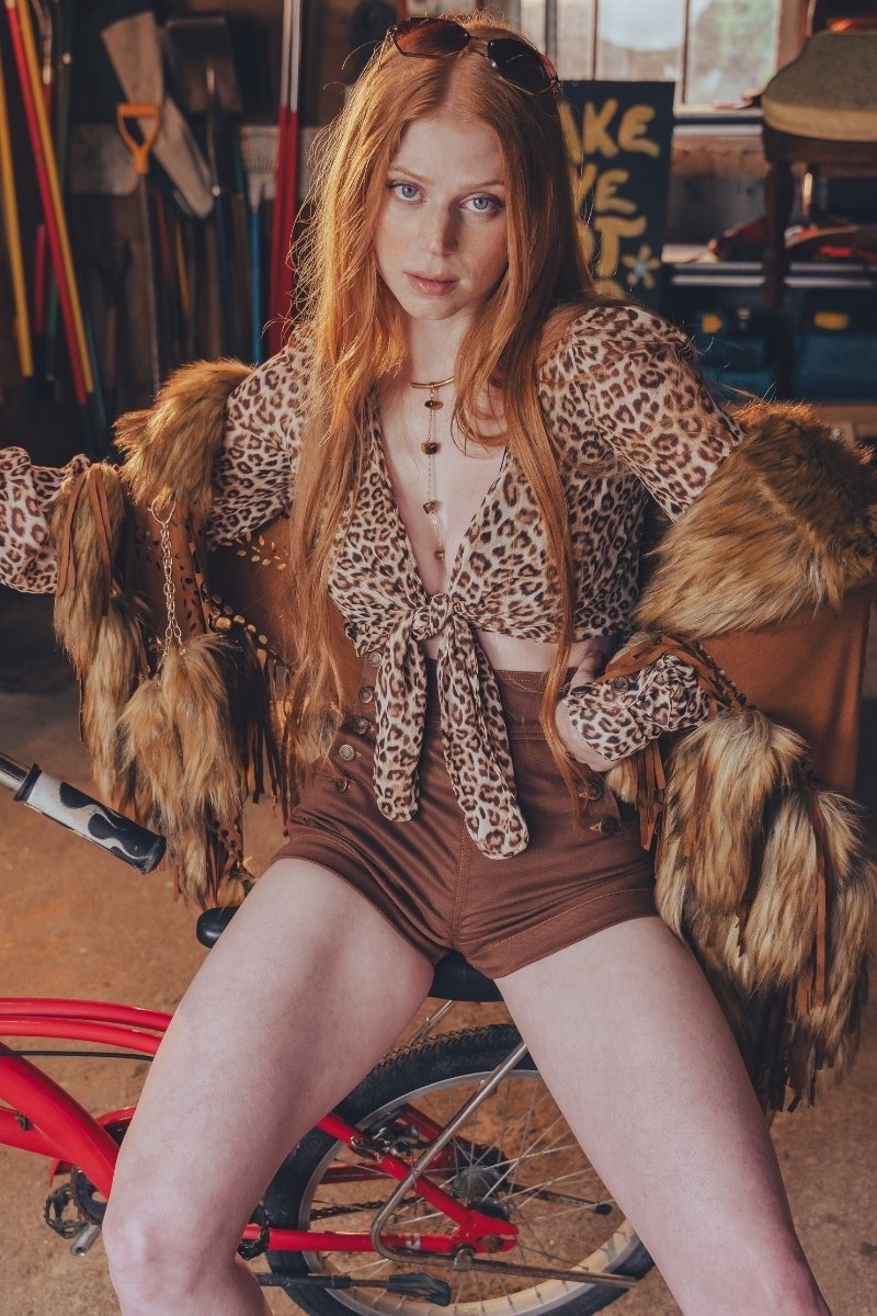 Model wearing chocolate Sally sailor shorts, a leopard-print tie-front top and a fur-trimmed jacket for a 70s-inspired festival outfit.