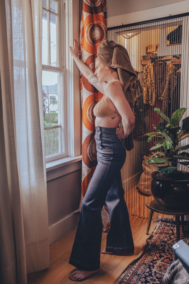 Model wearing dark navy high-rise sailor bell bottoms, showing the fitted upper leg and wide bell-shaped flare.