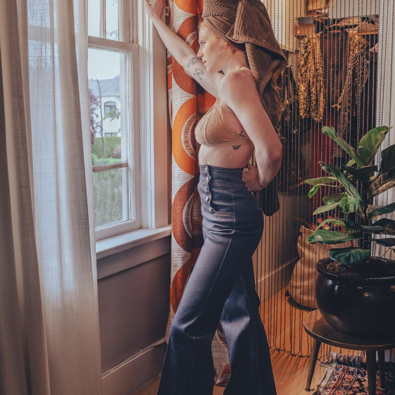 Model wearing dark navy high-rise sailor bell bottoms, showing the fitted upper leg and wide bell-shaped flare.