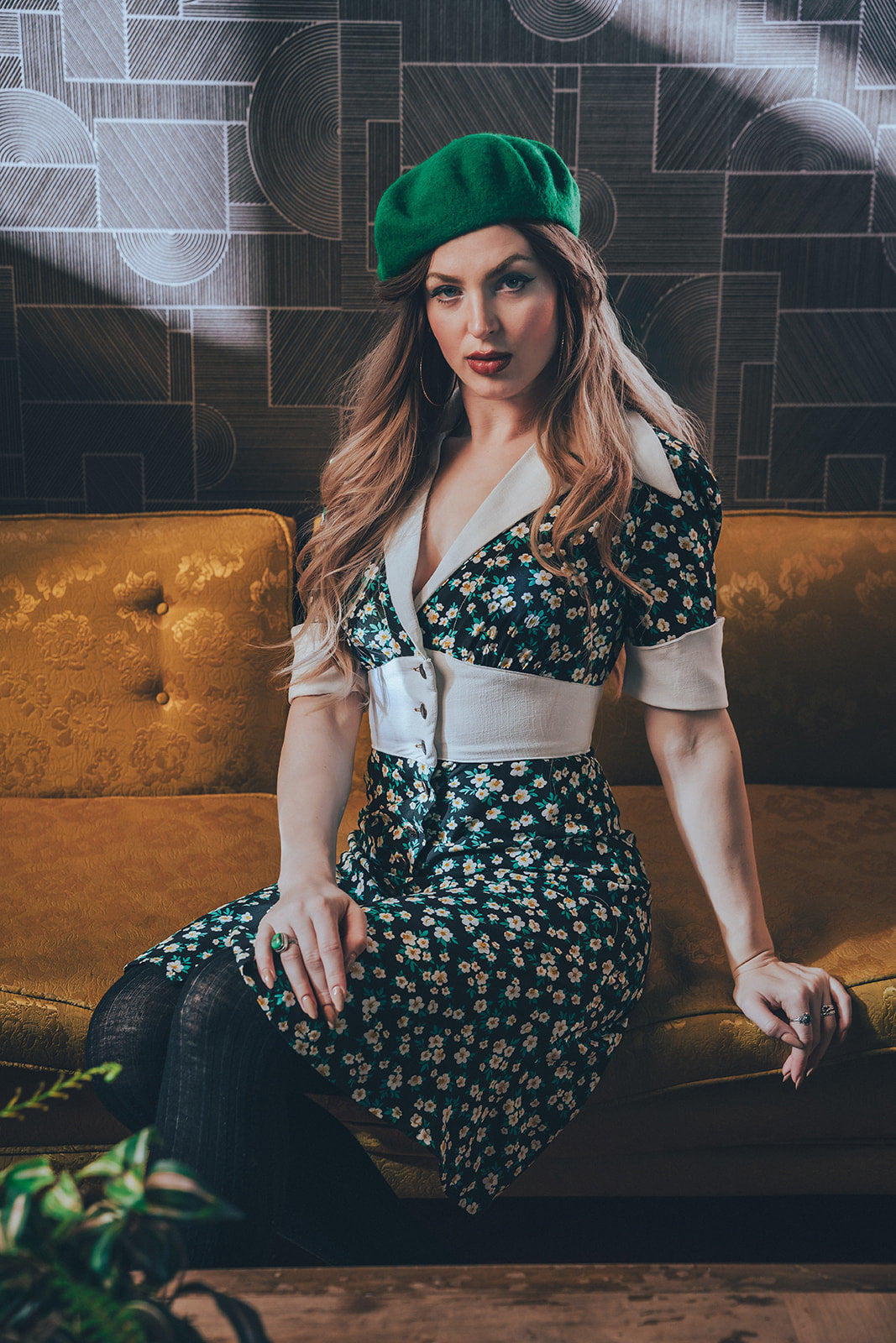 Girl sitting in a 1970s retro lounge wearing a vintage inspired flowered daisy dress exuding retro charm while lounging on a classic couch