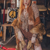 Person wearing a leopard print top and brown skirt with fur accents in an indoor setting.