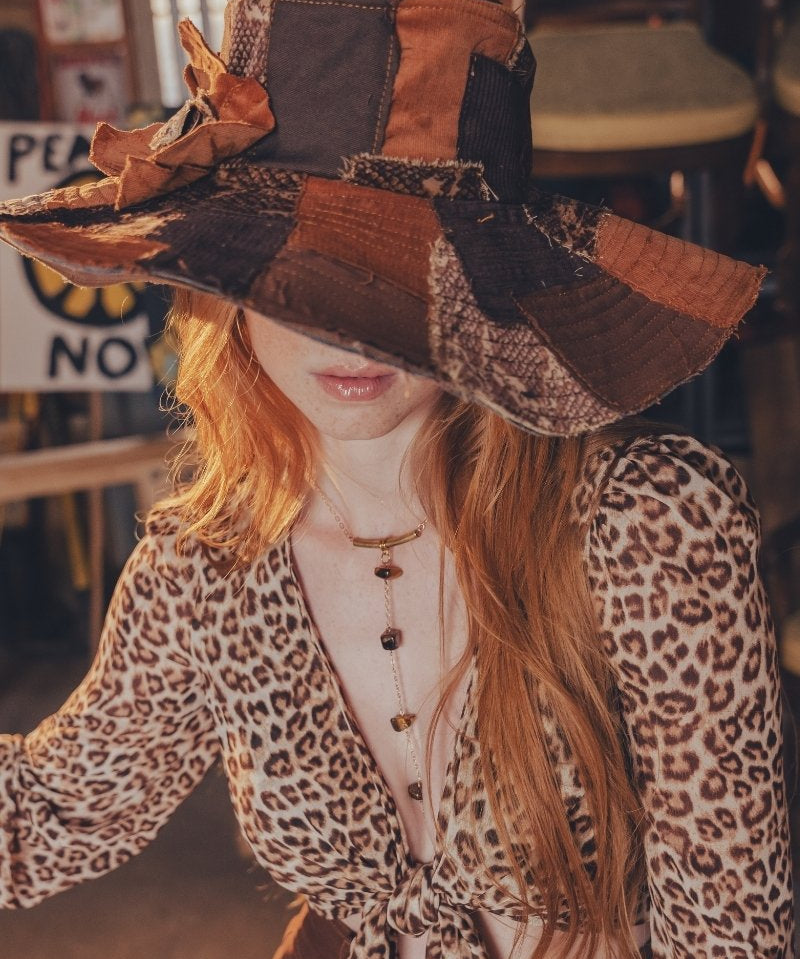 Person wearing a patchwork hat and leopard print outfit in an indoor setting