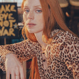 Woman with red hair wearing a leopard print top in an indoor setting.