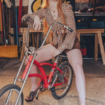 Woman sitting on a red bicycle in a workshop setting