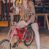 Woman sitting on a red bicycle in a workshop setting