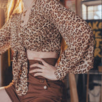 Person wearing a leopard print top and brown shorts in an indoor setting.
