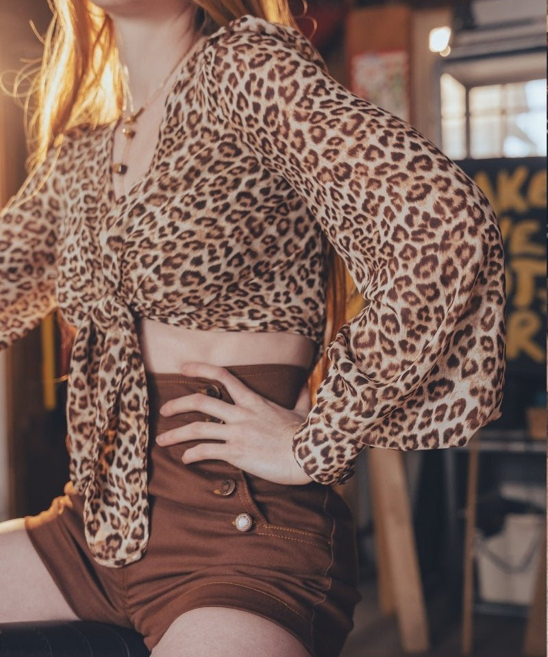 Person wearing a leopard print top and brown shorts in an indoor setting.