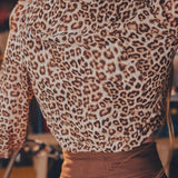 Person wearing a leopard print top and brown pants in an indoor setting