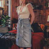 Woman standing in a bedroom with wooden walls and a bed in the background