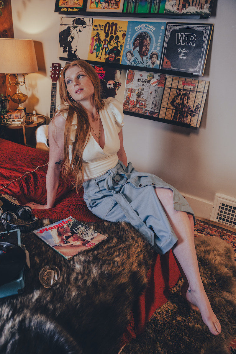 Woman sitting on a red couch in a room with vinyl records on the wall