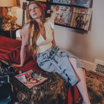 Woman sitting on a red couch in a room with vinyl records on the wall