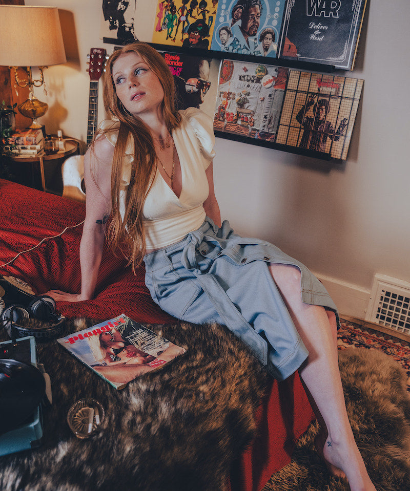 Woman sitting on a red couch in a room with vinyl records on the wall