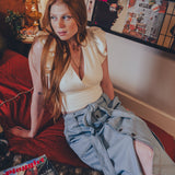 Woman sitting on a couch with a magazine and a dog, surrounded by posters on the wall.