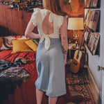 Woman standing in a cozy room with a guitar and books on the wall