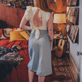 Woman standing in a cozy room with a guitar and books on the wall