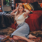 Woman sitting on a patterned rug in a cozy room with a red couch and laptop.