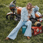 Woman sitting on a suitcase next to a motorcycle in a grassy field wearing Soul Sister since 1969