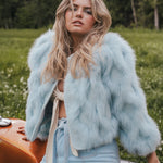 Woman wearing a light blue fur coat in a natural setting wearing Soul Sister since 1969