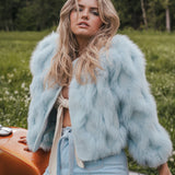 Woman wearing a light blue fur coat in a natural setting wearing Soul Sister since 1969
