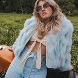 Woman in light blue fur coat and jeans sitting on a motorcycle in a field wearing Soul Sister since 1969.