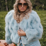Woman wearing a light blue fur coat and sunglasses outdoors wearing Soul Sister since 1969.