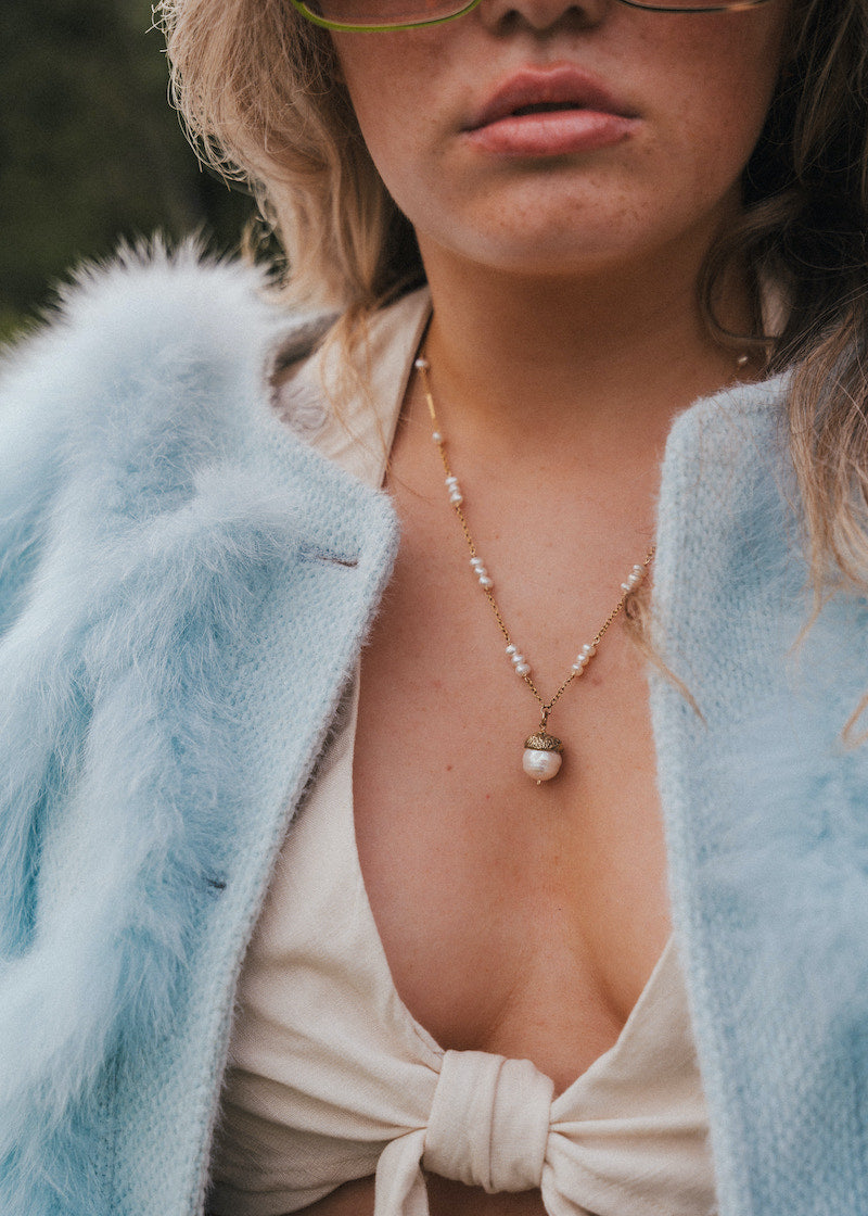Close-up of a person wearing a light blue fur coat and pearl necklace. wearing Soul Sister since 1969