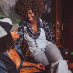 Two women sitting together, one with an afro, in a casual setting.