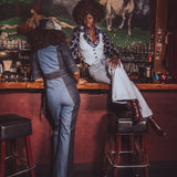 Two women in vintage clothing sitting at a bar with horse mural in the background